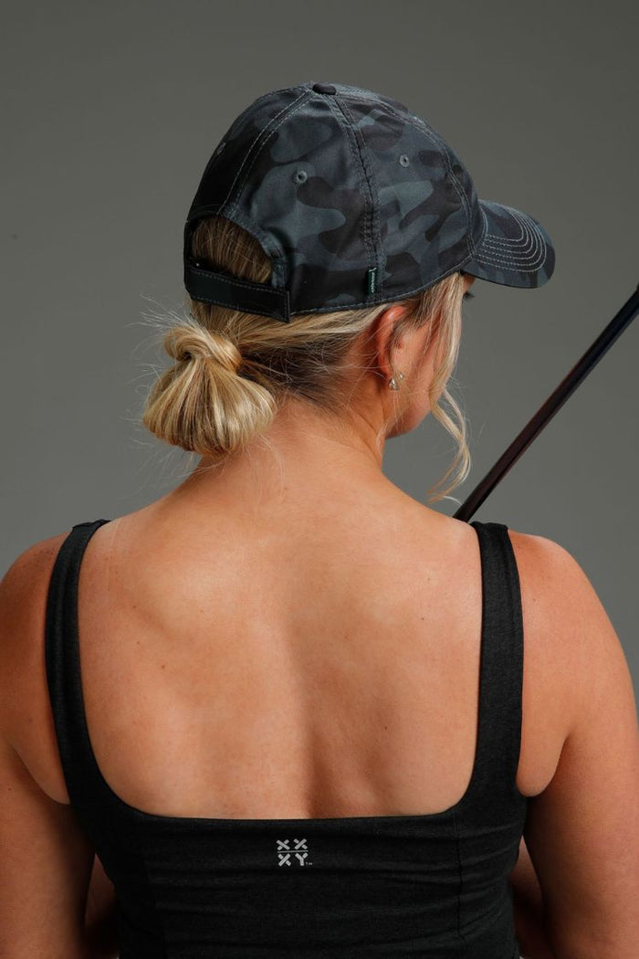 Person wearing a black tank top and camouflage cap with a gray background || Black Camo