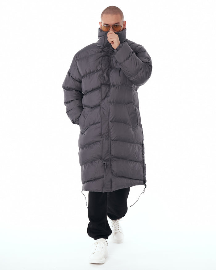 Martin Valen oversized long gray puffer coat, lower close-up showing hem, drawcord and model’s black pants