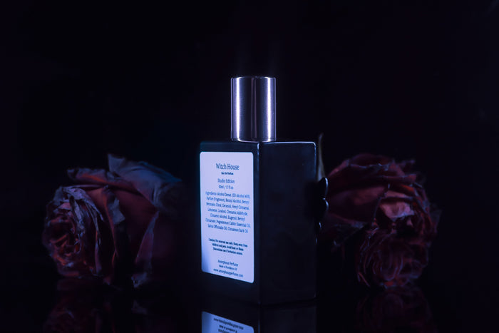 Perfume bottle with packaging on a dark background with dried roses