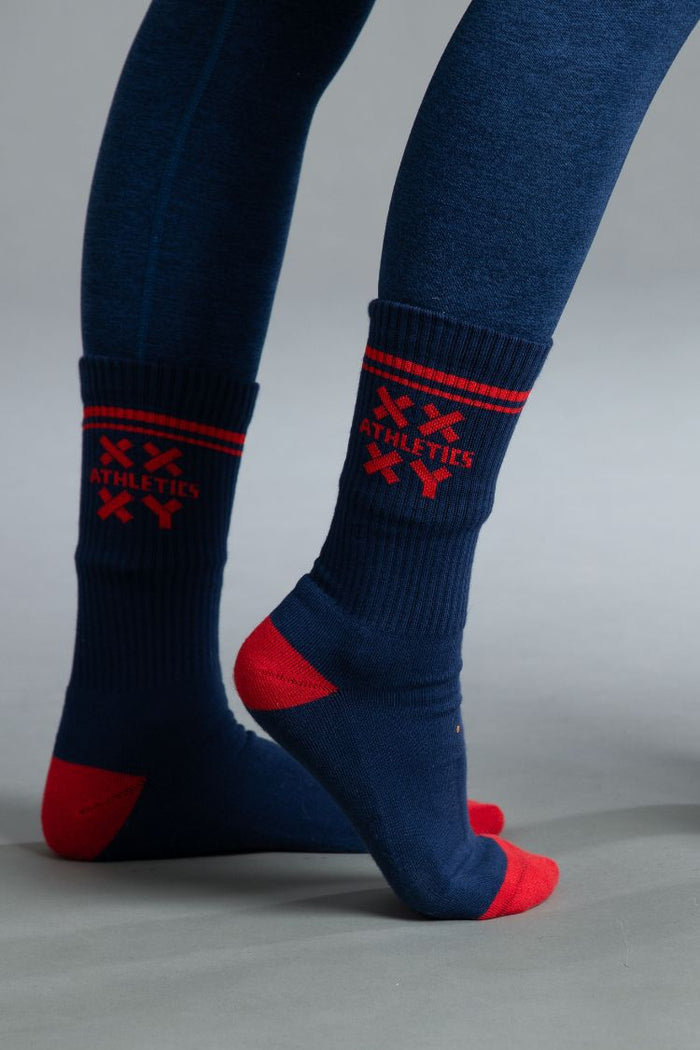 Navy socks with red accents worn by a person on a gray background || blue aster/red
