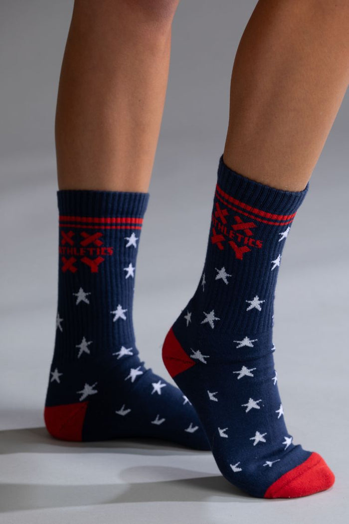 Navy blue socks with red and white star pattern worn by a person on a neutral background || patriotic with stars
