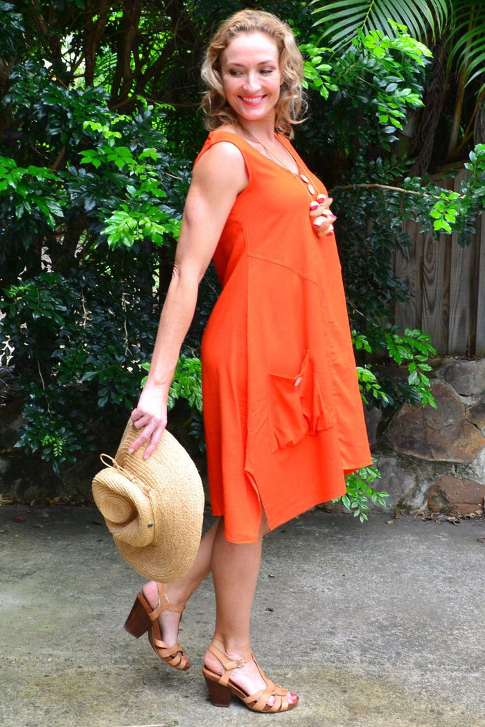 Ruby Rain Costa Rica Vivid Orange Tunic Dress hanging on a wooden hanger, showcasing its bright color and lightweight fabric.
