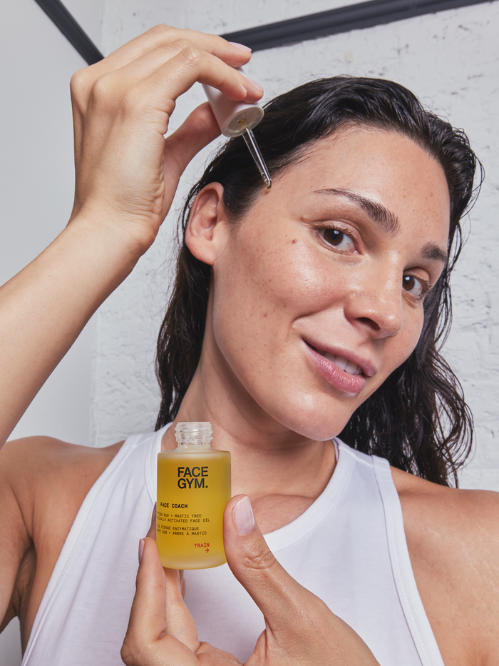 a woman holding a dropper and a bottle of face gym
