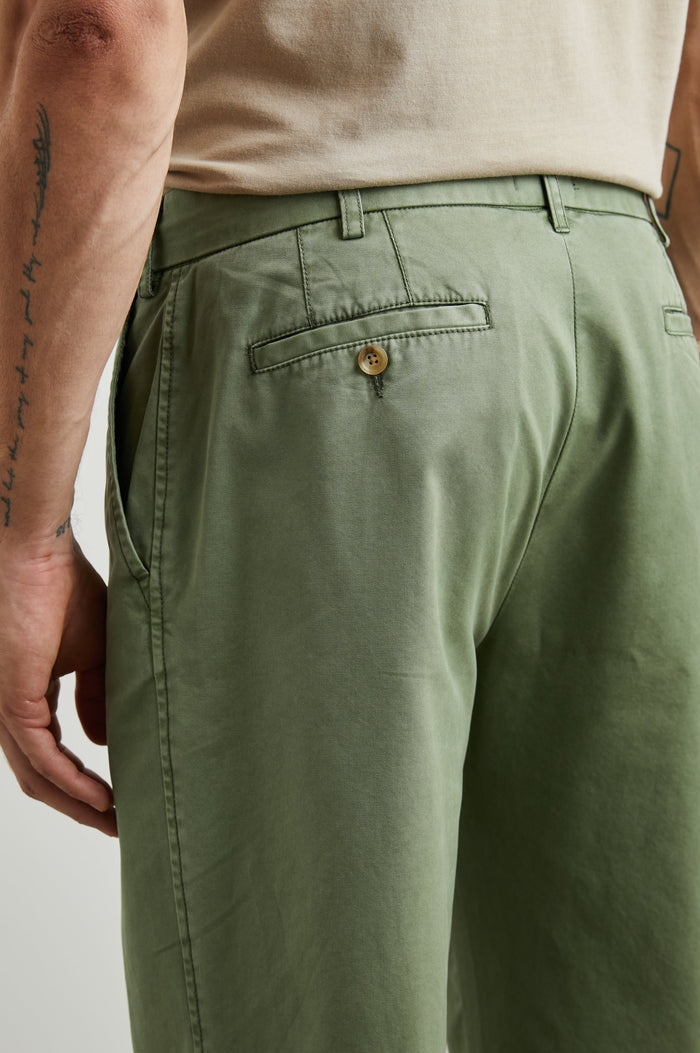 Garrett Pants with a Button Strap Closure at the Waist, Belt Loops, Two Front Pockets and Two Back Button Welt Pockets in Spring Olive Colorway - Back View Featured on Model