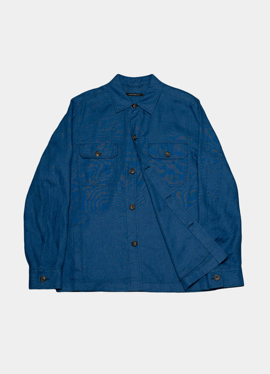 The Harbour Overshirt is a blue linen shirt with a collar, long sleeves, button front, and two flap chest pockets. Shown on a plain white background, it features a relaxed fit for effortless casual style.