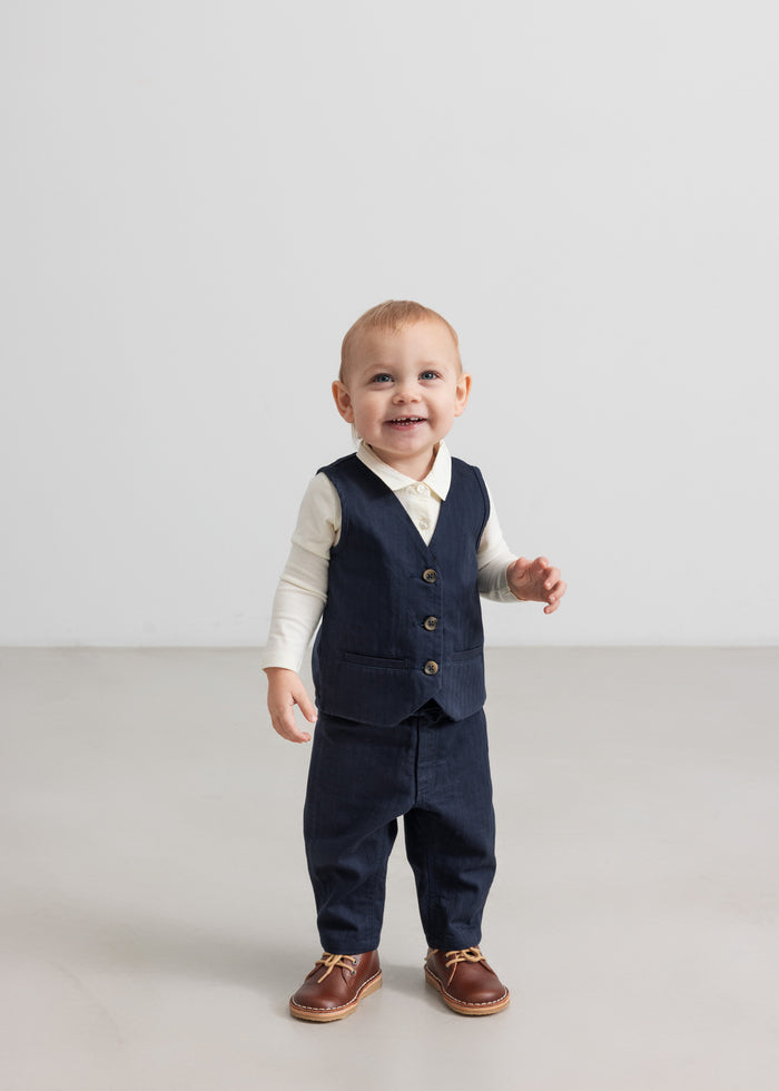 Baby wearing dark blue vest, shirt and pants in festive Christmas baby clothes