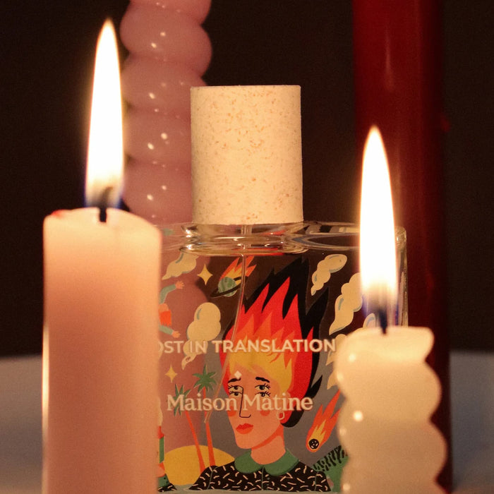 Maison Matine perfume polish bottle with lit candles on a dark background