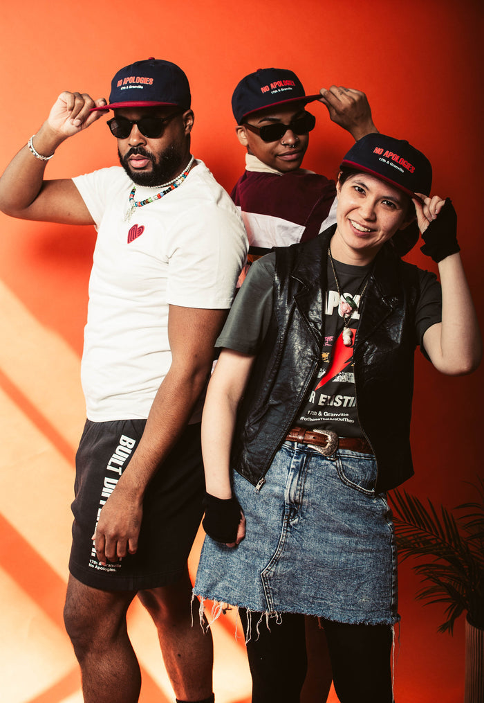 Three people wearing the No Apologies branded hat and clothing from 17th & Granville against an orange background