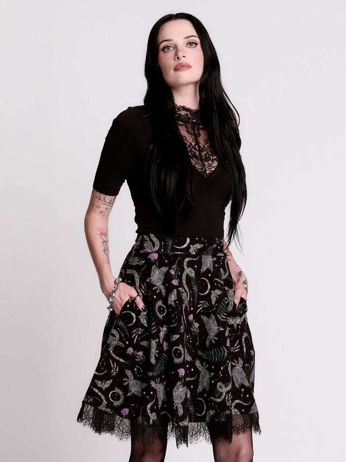 A  black flared skirt featuring a gray and purple gothic print with lace hem.