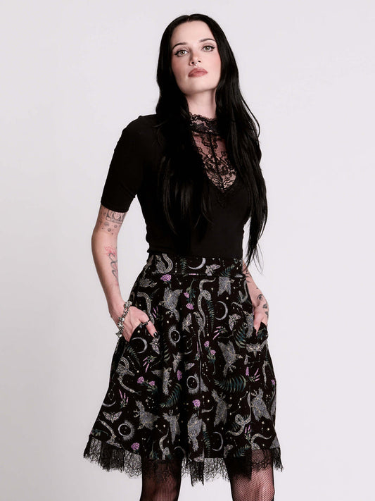 A  black flared skirt featuring a gray and purple gothic print with lace hem.