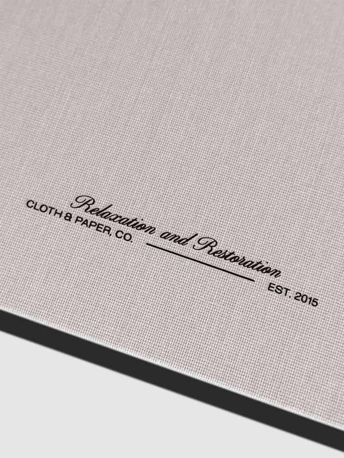 Closeup of fabric detailing and Rilassati tagline printed on folio. Text reads "Relaxation and Restoration / Cloth & Paper Co. / Est. 2015"