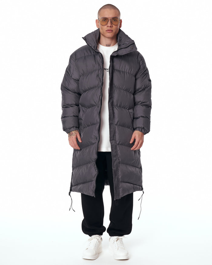 Martin Valen oversized long gray puffer coat front view with high collar raised, horizontal quilting and partially open zip
