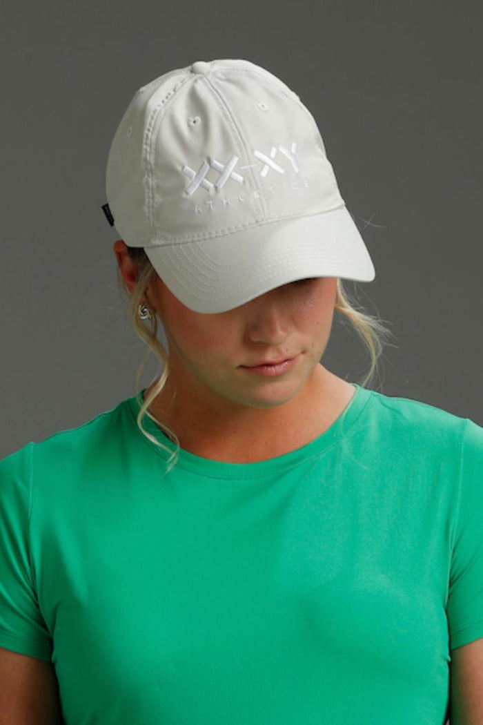 Person wearing a white cap with embroidered designs on a gray background
