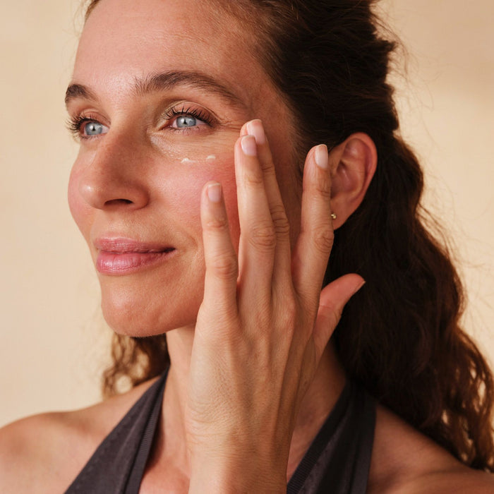 Mittelalte Frau trägt Santaverde XINGU refining eye cream unter ihrem Auge auf