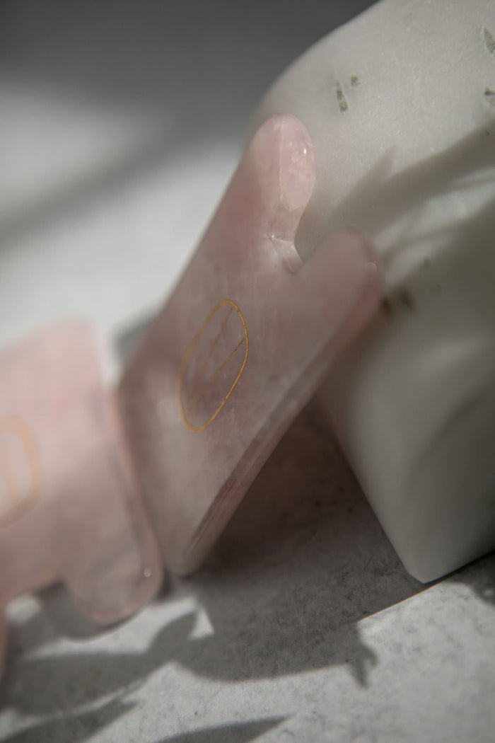Close-up of a smooth, polished Rose Quartz Gua Sha | Vie Healing tool resting against a white marble surface, highlighting its soft pink hue and natural texture for skincare and wellness.