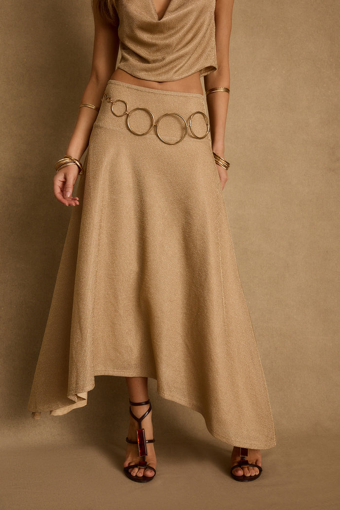 Gold lurex maxi skirt with asymmetrical hem and ring belt detail, worn with matching top.