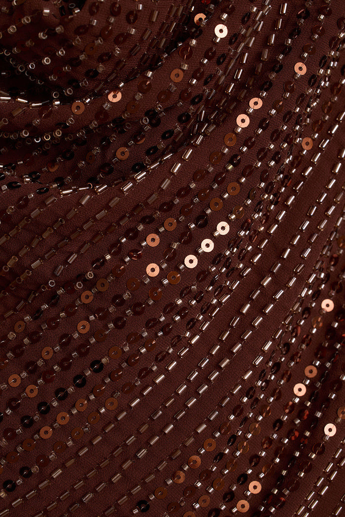 Close-up of espresso brown sequins and glass bead rows on a draped party top.