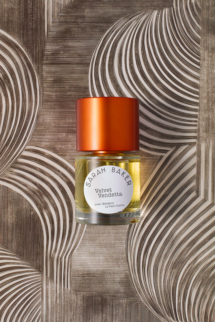 Sarah Baker Perfumes Velvet Vendetta 50ml Extrait de Parfum bottle with red cap on sculptural wood grain background