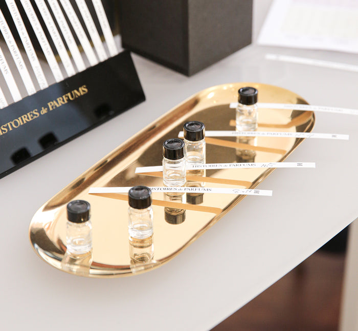 small perfume vials with scent strips on a small tray placed on a table.